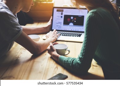 Cropped image of group of young students are watching movie on laptop computer, while are sitting at wooden table in loft. Group of friends using net-book during meet in modern coffee shop interior - Shutterstock ID 577535434