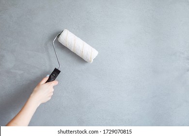 Cropped Image of a hand Holding a Paint Roller While Painting a House Wall. 
