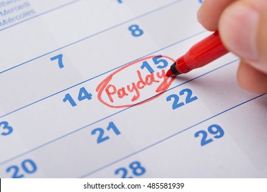 Cropped Image Of Hand Marking Payday On Calendar