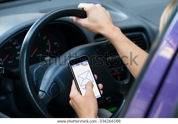 Cropped\
image of hands checking message while driving\
car