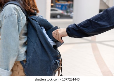 Cropped image of hands of pickpocket thief stealing wallet from backpack of tourist girl