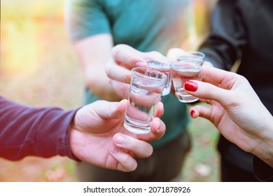 Cropped image of hands toasting with vodka shots. Friends drinking shot alcohol outdoors. Young people with Shot drink outdoors. Close up