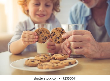 Cropped image of handsome grandpa and grandson drinking milk and eating cookies together at home - Powered by Shutterstock