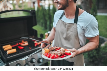 Cropped image of handsome man is making grill barbecue outdoors on the backyard. Bbq party.