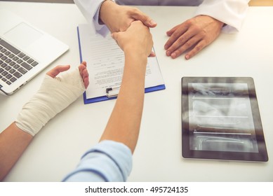 Cropped image of handsome medical doctor shaking hands with female patient while working in his office