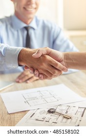 Cropped Image Of Handsome Middle Aged Realtor In Classic Shirt Shaking Hands With His Clients And Smiling While Sitting In Office