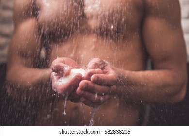 Cropped image of handsome naked Afro American man using a soap while taking shower