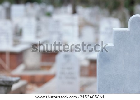 Cropped image of headstone at Muslim cemetery. Background of blurred graveyard.