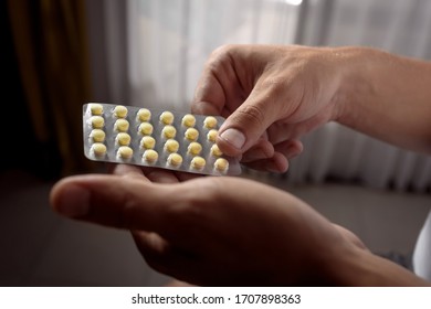 Cropped Image Of Human Hands Taking Tablet Out From Blister Pack