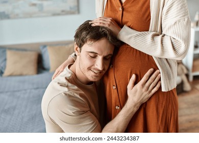 Cropped image of husband listening to baby in pregnant wife belly, hugging parents - Powered by Shutterstock