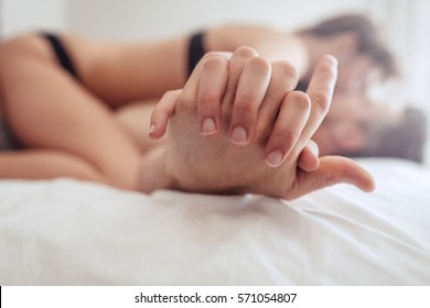 Cropped Image Of Intimate Couple Holding Hands While Having Sex On Bed.