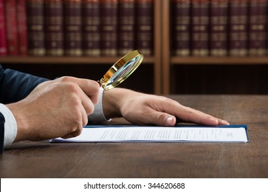 Cropped image of lawyer examining documents with magnifying glass in courtroom - Shutterstock ID 344620688