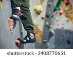 Cropped image of legs in special shoes standing on artificial rock. Bouldering, wall climbing activity . Concept of sport, bouldering, sport climbing, hobby, active lifestyle, school, training course