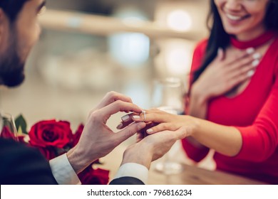 Cropped image of loving couple is spending time together in modern restaurant. Attractive young woman in dress and handsome man in suit are having romantic dinner. Celebrating Saint Valentine's Day. - Powered by Shutterstock