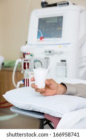 Cropped Image Of Male Cancer Patient Holding Glass Of Crushed Ice In Dialysis Room At Hospital