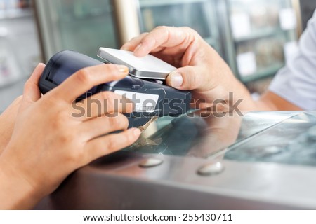 Cropped image of male customer making payment through smartphone in butchery