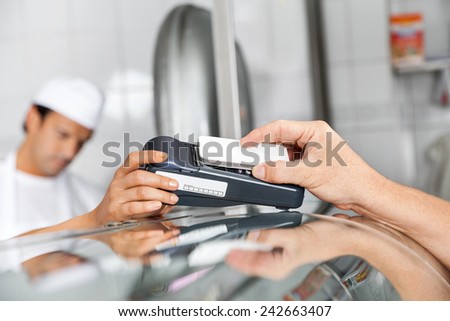 Cropped image of male customer paying through smartphone in butchery