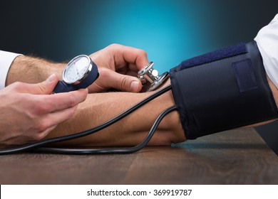 Cropped Image Of Male Doctor Checking Blood Pressure Of Patient At Table