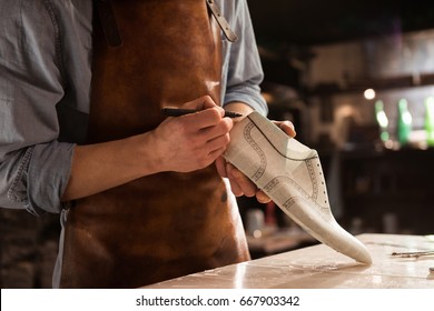 Cropped image of a male shoemaker making design for a new shoes at his workshop - Powered by Shutterstock