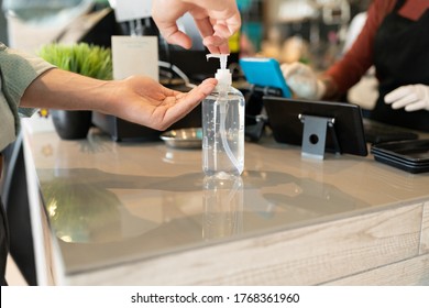 Cropped Image Of Man Applying Sanitizer On Hand At Checkout Counter In Coffee Shop