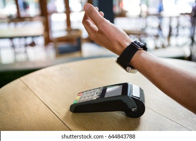 Cropped Image Of Man Hand Using Smart Watch To Express Pay In Coffee Shop