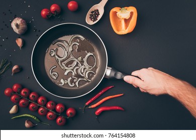 Cropped Image Of Man Holding Frying Pan Above Gray Table