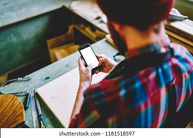 Cropped Image Of Man Holding Modern Smartphone With Mock Up Screen Text Messages,back View Of Handyman Using Mobile Phone Connected To 4G Internet Checking Clients Order On Web Page In Workshop