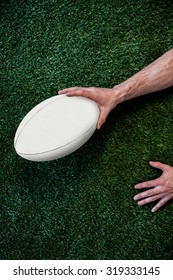 Cropped Image Of A Man Holding Rugby Ball Over The Grass