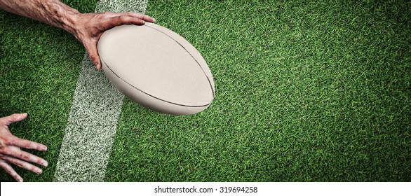 Cropped image of a man holding rugby ball against pitch with line - Powered by Shutterstock