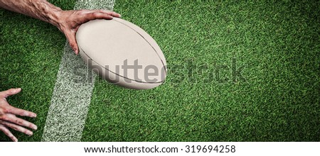 Cropped image of a man holding rugby ball against pitch with line