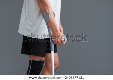 Cropped image of man with injured leg leaning on crutch when walking