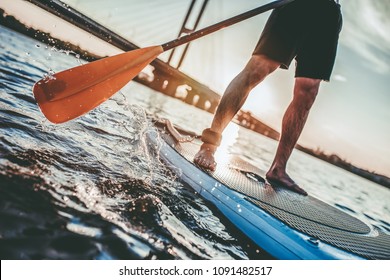 Cropped Image Of Man On Stand Up Paddle Board. Having Fun On SUP Board During Sunset. Active Lifestyle.