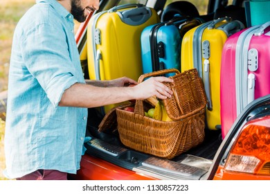 Cropped Image Of Man Packing Picnic Basket At Car Trunk