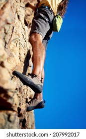Cropped image of a man's legs finding a foothold while rock climbing