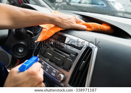 Cropped image of mature male worker cleaning car dashboard