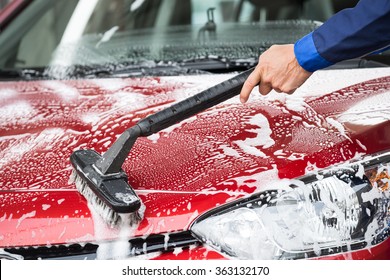 Cropped Image Of Mature Washer Cleaning Red Car At Service Station