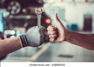 Cropped image of mechanics working in auto service. One is holding a spanner while the other is showing Ok sign - Shutterstock ID 618006542