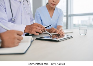 Cropped image of medical workers discussing information on tablet computer
