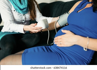 Cropped image of a midwife measuring blood pressure of a pregnant woman