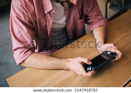 Cropped image of millennial male holding gamepad controller for playing video game indoors, unrecognizable man using joypad switch and 4G internet connection for winning online multi tournament