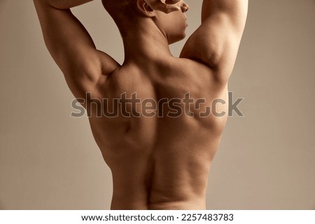 Cropped image of muscular, relief male shirtless body over grey studio background. Strong, healthy back. Concept of men's health and beauty, body and skin care, fitness, youth. Body art