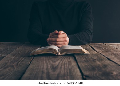 cropped image of nun sitting at table with bible and praying 
