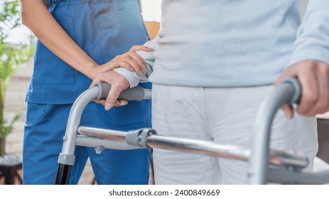 Cropped image of nurse helping senior woman to walk with walker at home. Walking movement disability impairment, handicapped person. Senior life concept - Powered by Shutterstock