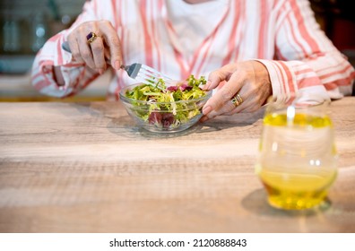 Cropped Image Of Old Lady Having Healthy Snack And Glass Of Lemonade. Senior Woman Eating Fresh Salad At Her Wooden Kitchen Table. Copy Space