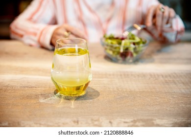 Cropped Image Of Old Lady Having Healthy Snack And Glass Of Lemonade. Senior Woman Eating Fresh Salad At Her Wooden Kitchen Table. Copy Space