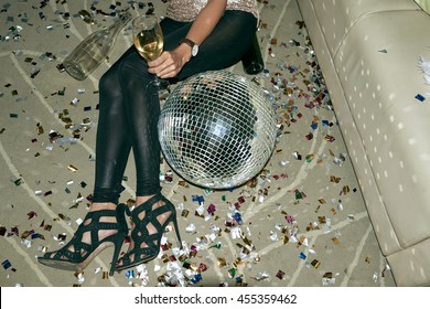 Cropped image of party woman lying on floor next to disco ball
