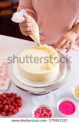 Cropped image of a pastry chef decorating cake with frosting in the kitchen