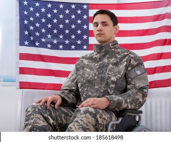 Cropped image of patriotic soldier sitting on wheel chair against American flag - Powered by Shutterstock