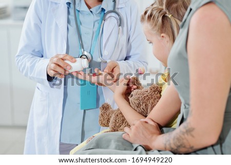 Cropped image of pediatrician giving medicie to little girl with lollipop