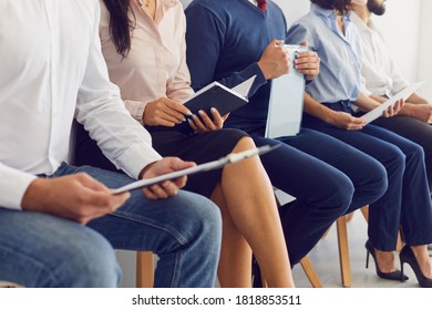Bild von Menschen, die auf Stühlen in einer Warteschlange sitzen und Papier in ihren Händen halten. Stellenbewerber. Gruppe unerkennbarer Bewerber, die auf ein Bewerbungsgespräch warten.